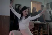 Restaurant patrons watch a Chinese woman in a kung fu stance.