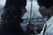 A still from 'The Great Barrier' super 8mm short film - two young lovers under an umbrella in front of a motorway viaduct.