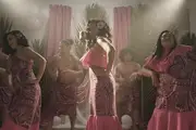 Three Samoan women dance on stage in bright, modern Pacific Island dresses.